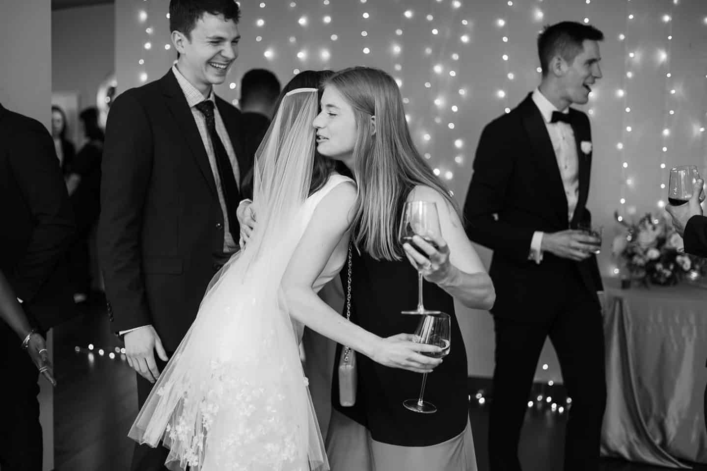 Candid emotional moment of bride hugging wedding guest at Detroit wedding reception.